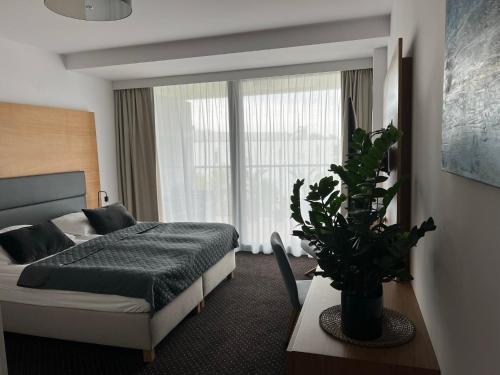 科沃布热格Seaside Park Hotel Kołobrzeg apartament 27 metrów szczęścia的一间卧室配有一张床和盆栽植物