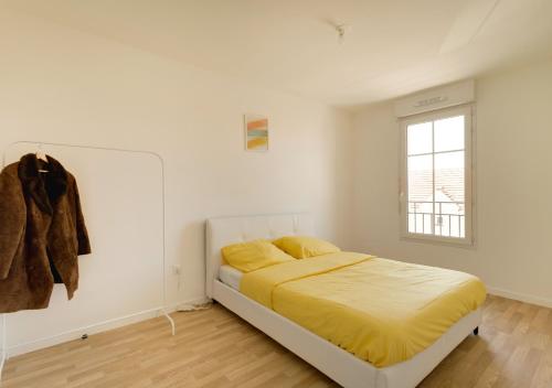 马恩河畔维列Au CALME entre DISNEY et PARIS的一间卧室配有一张带黄色床单的床和一扇窗户。