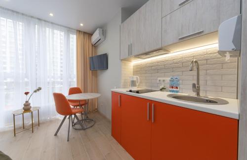 基辅MYFREEDOM Апартаменти метро Сирець的厨房配有橙色橱柜、水槽和桌子