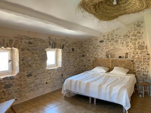 AspiranChambres d'hôtes La Tour d'Aspiran的石墙客房的卧室配有床