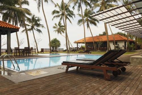 瓦都瓦蓝色海滩酒店的棕榈树游泳池旁的躺椅