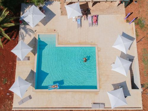莱乌卡Masseria Serine的享有带白色遮阳伞的游泳池的顶部景致