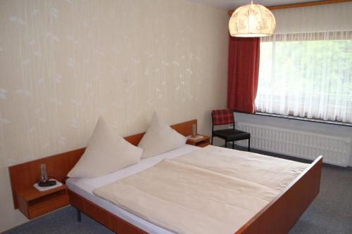 Ober-KainsbachGasthaus Zum Hohenstein的卧室配有床、椅子和窗户。