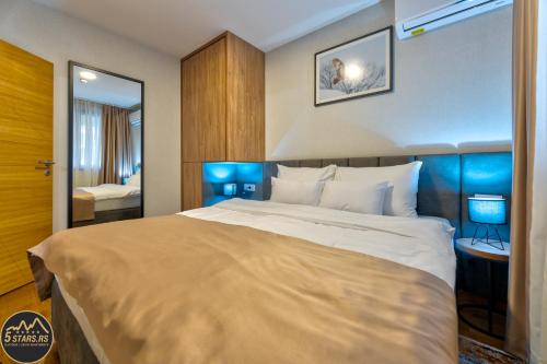 兹拉蒂博尔5 STARS - Luxury Premium WELLNESS RESORT Zlatibor的一间卧室配有一张大床和镜子