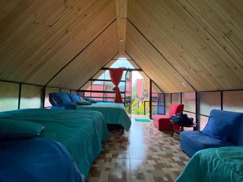 苏埃斯卡Hospedaje Villa Rosita Suesca的帐篷内的房间,配有三张床和两把椅子