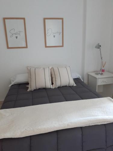 西波列蒂Departamento Nuevo en Cipolletti的卧室内的一张床铺,墙上有两张照片