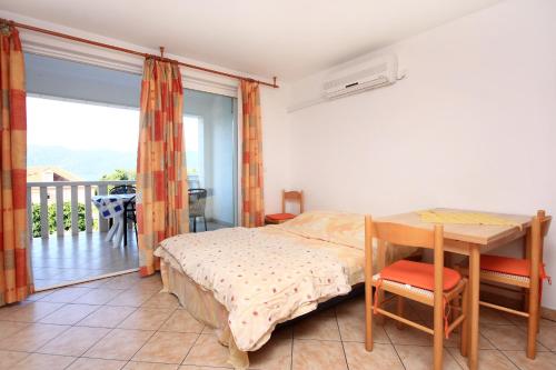 库希斯特Apartments by the sea Viganj, Peljesac - 10189的一间卧室配有一张床铺和一张桌子,并设有一个阳台