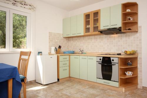 库希斯特Apartments with a parking space Kuciste - Perna, Peljesac - 10161的厨房配有白色橱柜、炉灶和冰箱。