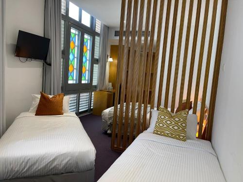新加坡The Assembly Place, A Co-living at Mayo的一间卧室设有两张床和彩色玻璃窗。