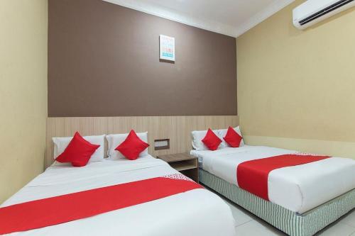 怡保Silibin Times Inn Hotel的两张位于酒店客房的床铺,配有红色枕头