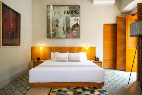瓦哈卡市Casa Carmen Morelos的卧室配有一张大床,墙上挂有绘画作品