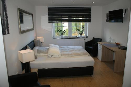 Gangelt布鲁玛乐姆乐酒店的一间卧室配有一张床、一张书桌和两个窗户。