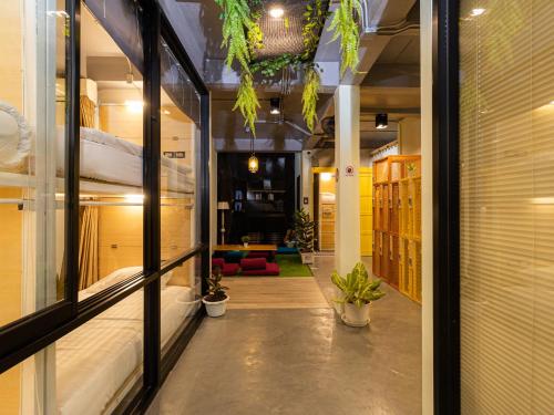曼谷Khao San Social Capsule Hostel的走廊上设有床铺和植物的房间