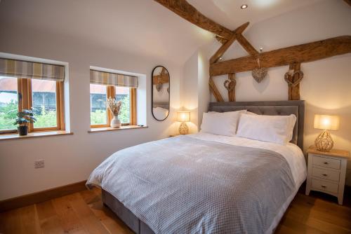 赫里福德Bramble Cottage - Cosy 2 Bed With Deluxe HOT TUB & Log Burner的一间卧室设有一张床和两个窗户。