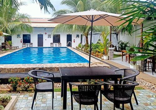 邦劳RedDoorz Plus at Palm Rise K Diving Resort Panglao Bohol的游泳池旁带遮阳伞的桌子