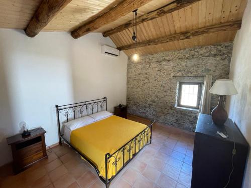 LaboniaAgriturismo Tenuta Feraudo的一间卧室设有黄色的床和砖墙