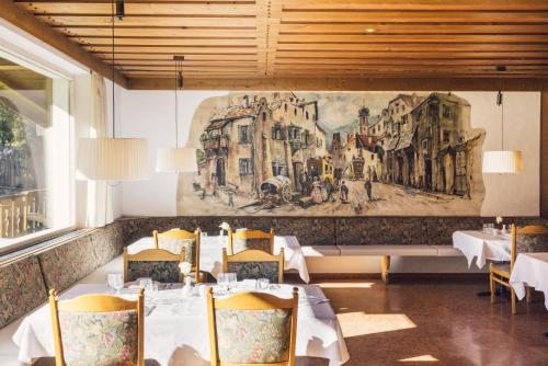 卢塔戈波斯特酒店的餐厅设有桌椅,墙上挂有绘画作品