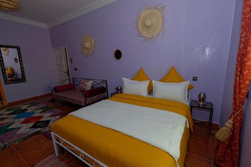 瓦尔扎扎特Riad Parfums de OUARZAZATE的一间卧室配有一张带黄色和白色枕头的大床