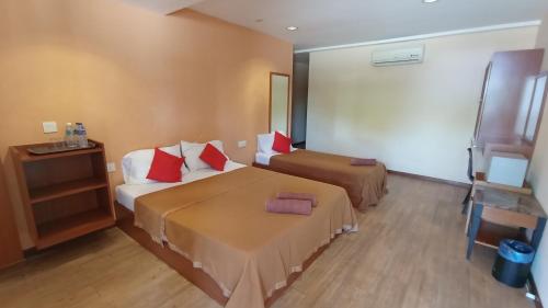 马六甲Straits Settlement Inn的酒店客房 - 带两张带红色枕头的床