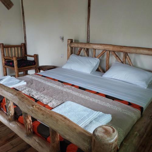 KatunguruSongbird Safari Lodge & Campsite的一张带两个枕头的木床和毛巾