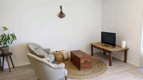 乌瑞基尼Maison Caiada的客厅配有两把椅子、一台电视和一张桌子