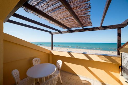 卡托利卡Rex Residence Hotel的阳台配有桌椅,享有海滩美景。