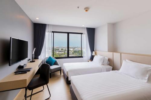 曼谷Best Western Nada Don Mueang Airport hotel的酒店客房设有两张床、一张桌子和一台电视。