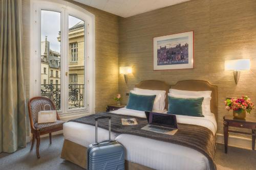 巴黎德拉维尼亚酒店的酒店客房,配有一张带笔记本电脑的床