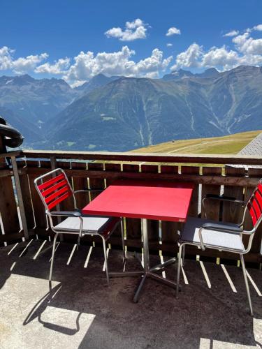 菲施Mischabelblick的山景阳台上摆放着红色的桌椅
