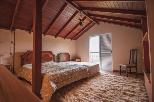 兰舒凯马杜Casa Fuchsia Régia em Rancho Queimado/SC的一间卧室设有一张床和一个大窗户