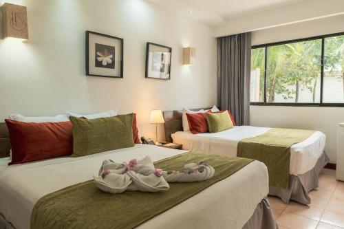 拉罗马纳Hotel Silvestre的两张位于酒店客房的床,配有毛巾