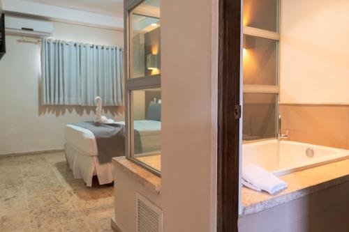拉罗马纳Hotel Silvestre的客房设有带浴缸的浴室和一张床