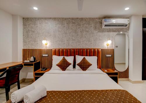 古瓦哈提Hotel Sai Rain Tree的酒店客房带一张床、一张书桌和一面镜子
