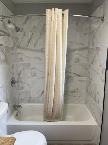 丹伯里Golden Hill Inn-Danbury的白色的浴室设有浴缸和淋浴帘