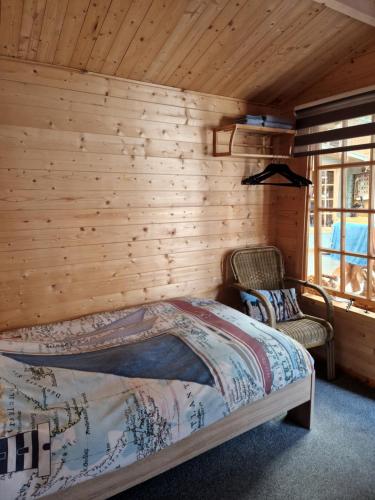 劳雷尔苏格Slaaphuisjes LauwersmeerPlezier!的一间卧室设有木墙、一张床和两把椅子