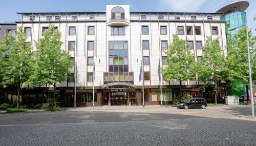 莱比锡Dorint Hotel Leipzig的一座大型建筑,前面有停车位