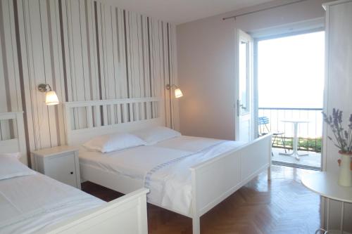 伯德古拉Apartments by the sea Podgora, Makarska - 12465的一间白色卧室,配有两张床和一个阳台