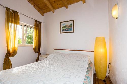 博格莫耶Secluded fisherman's cottage Cove Smokvina, Hvar - 13608的卧室配有白色的床和黄色灯
