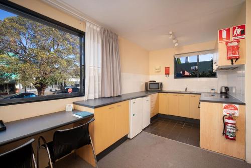悉尼Drummoyne Furnished Apartments的一间设有黄色橱柜和大窗户的厨房