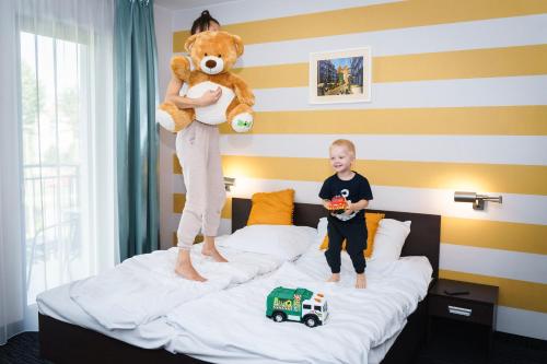 格但斯克金郁金香格但斯克公寓酒店的一个小男孩和泰迪熊站在床上