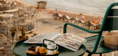 特拉维夫特拉维夫海滩皇冠假日酒店的绿桌,书,杯,报纸