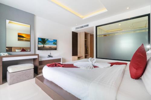 芭东海滩Paripas Patong Resort - SHA Extra Plus的卧室配有带红色枕头的大型白色床