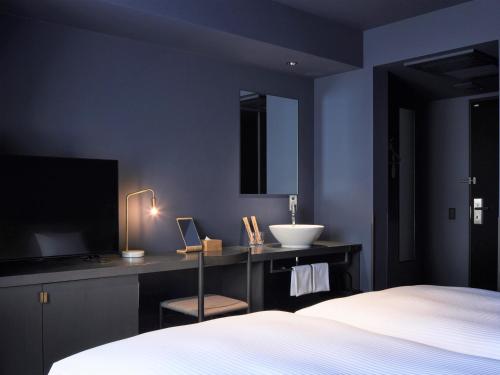 札幌hotel androoms Sapporo Susukino的一间卧室配有一张床、一个水槽和一台电视
