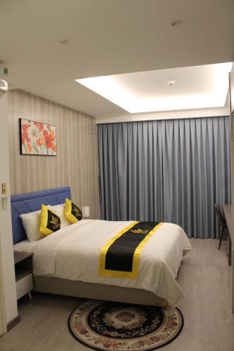 胡志明市THE QUEENDOR BOUTIQUE HOTEL的一间卧室配有一张大床,提供黄色和黑色的枕头