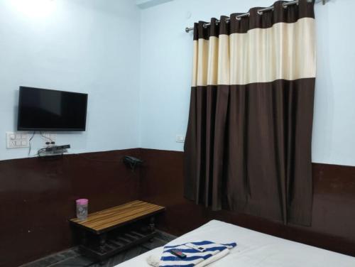 珀勒德布尔Suresh Guest House & Hotel By WB Inn的配有床、窗帘和电视的房间
