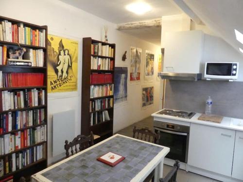 考特尼B2 Appartement entier centre ville tout confort的厨房配有桌子和书架,书架上摆放着书籍