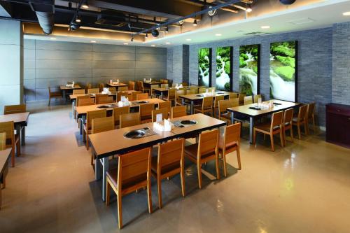 平昌平昌韩华度假酒店的餐厅设有木桌、椅子和窗户。