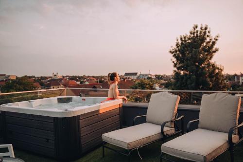奥拉迪亚Hotel Glory的坐在阳台上热水浴缸中的女人