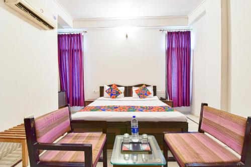 斋浦尔FabHotel Gitanjali的一间卧室配有一张床、两把椅子和一张桌子
