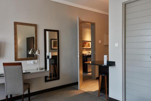 哈博罗内Regent Select Hotel的客房设有书桌、桌子和镜子